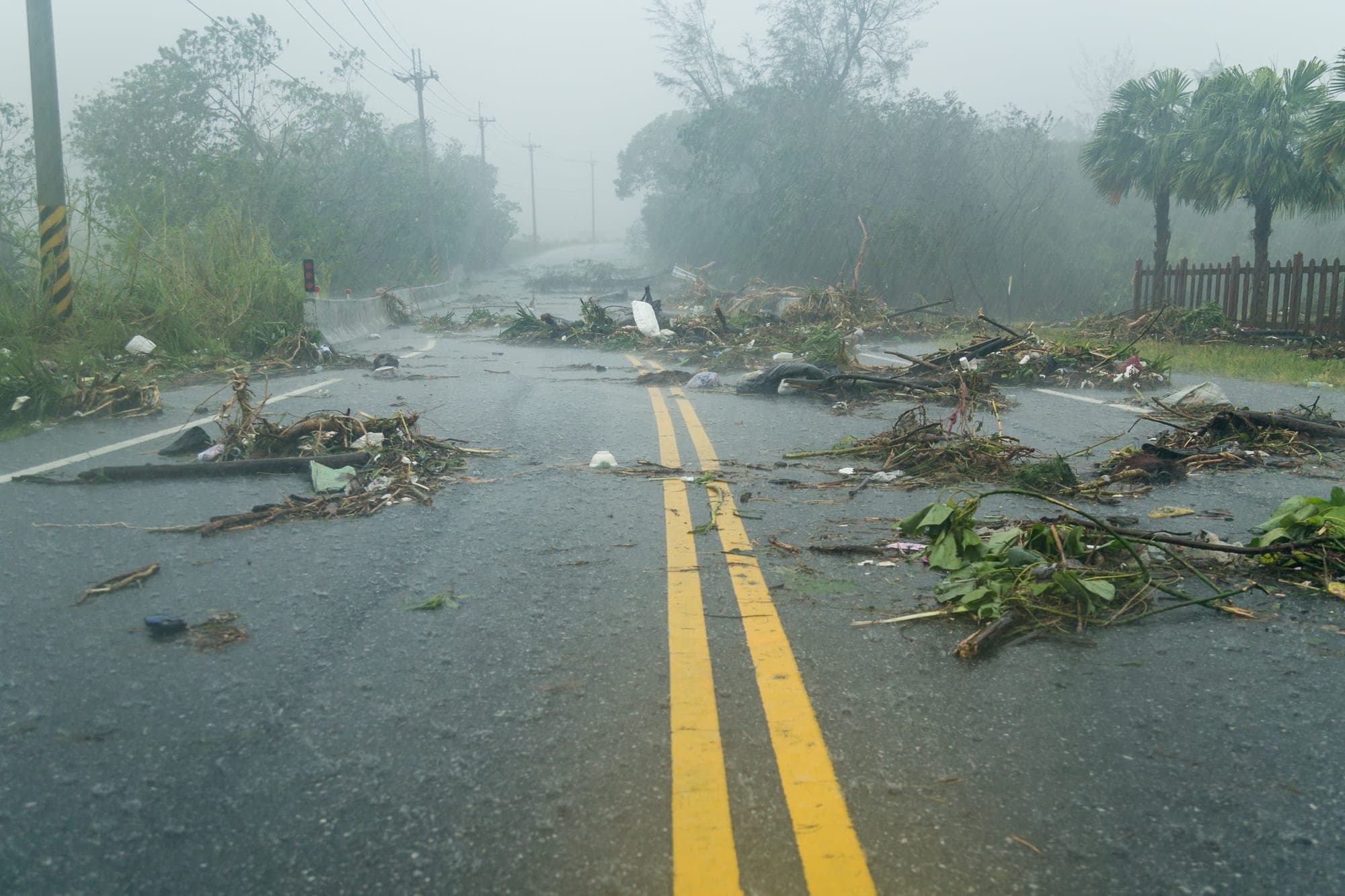Storm debris strewn across a wet, flooded roadway