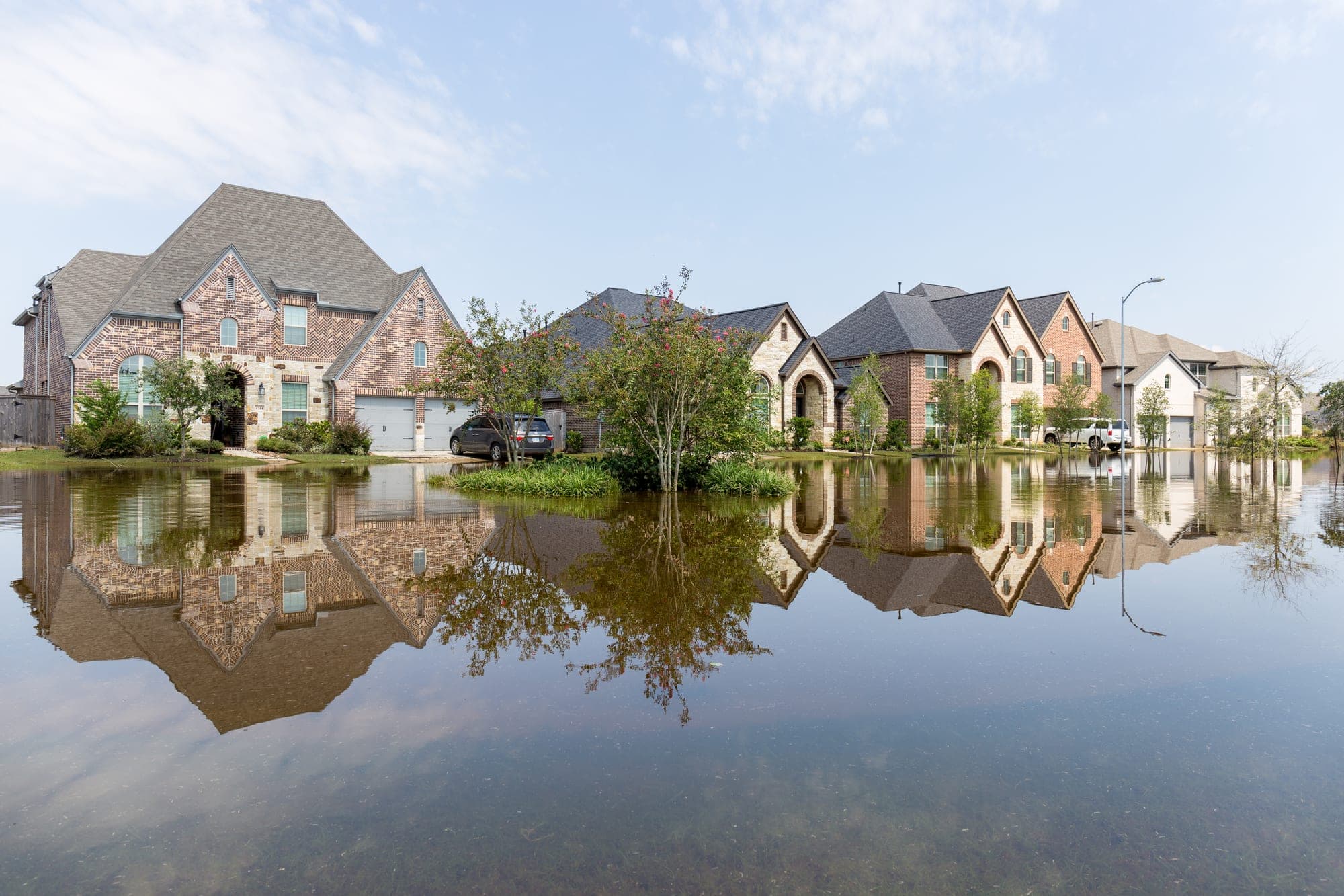 Floodwater surrounding brick homes in a residential neighborhood