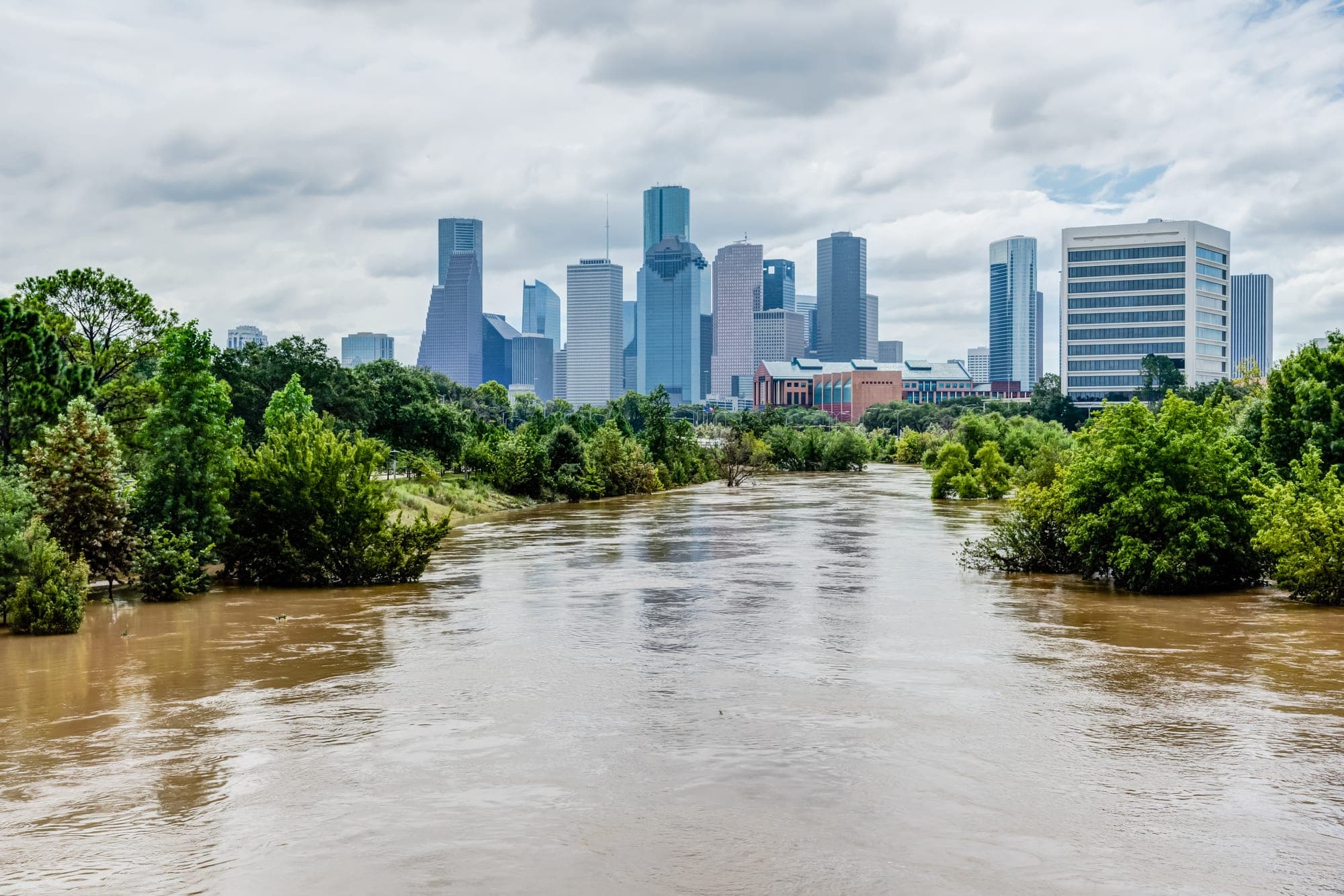 Swollen, muddy floodwaters rising near a city skyline