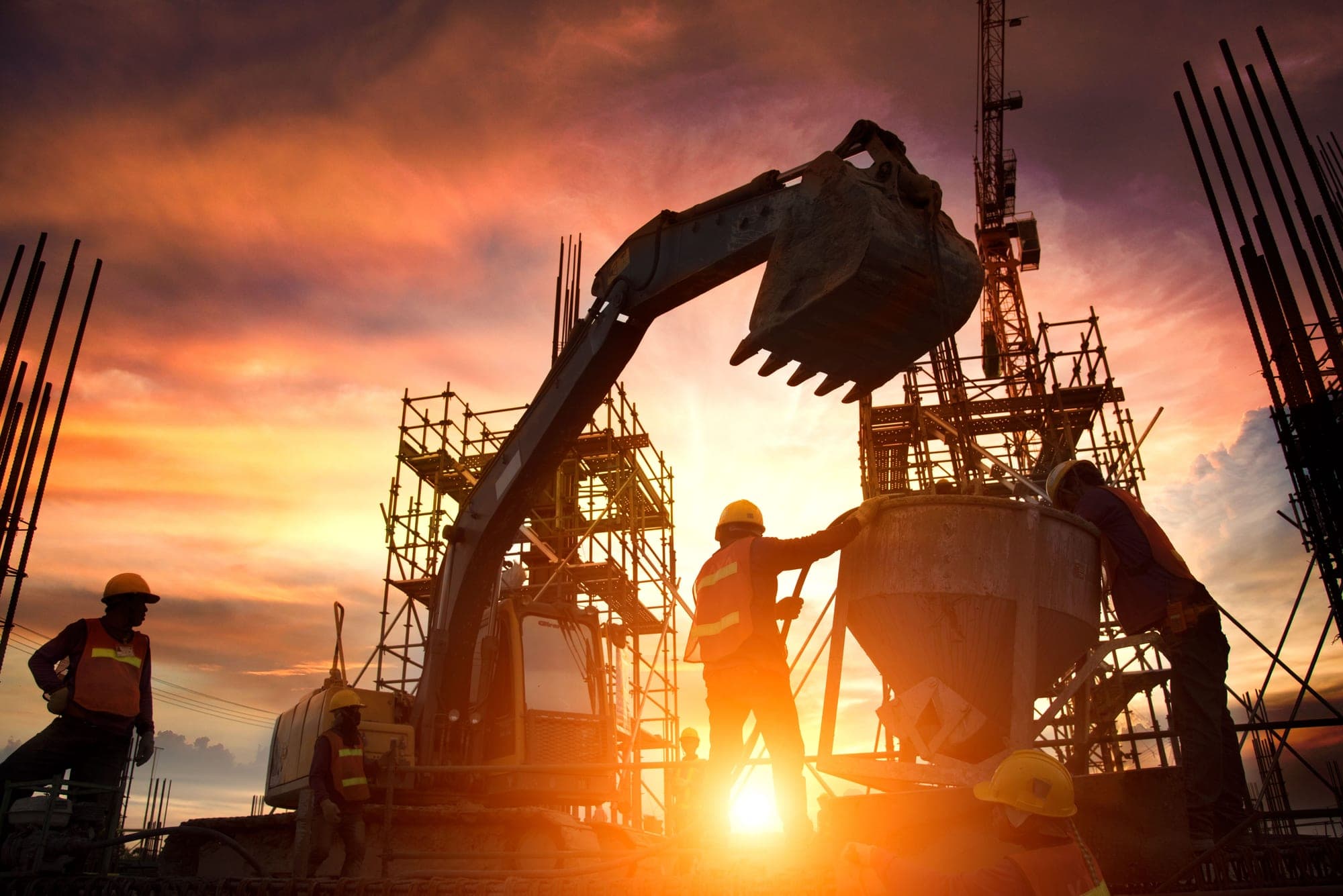 Excavator and construction crew silhouetted against a sunset