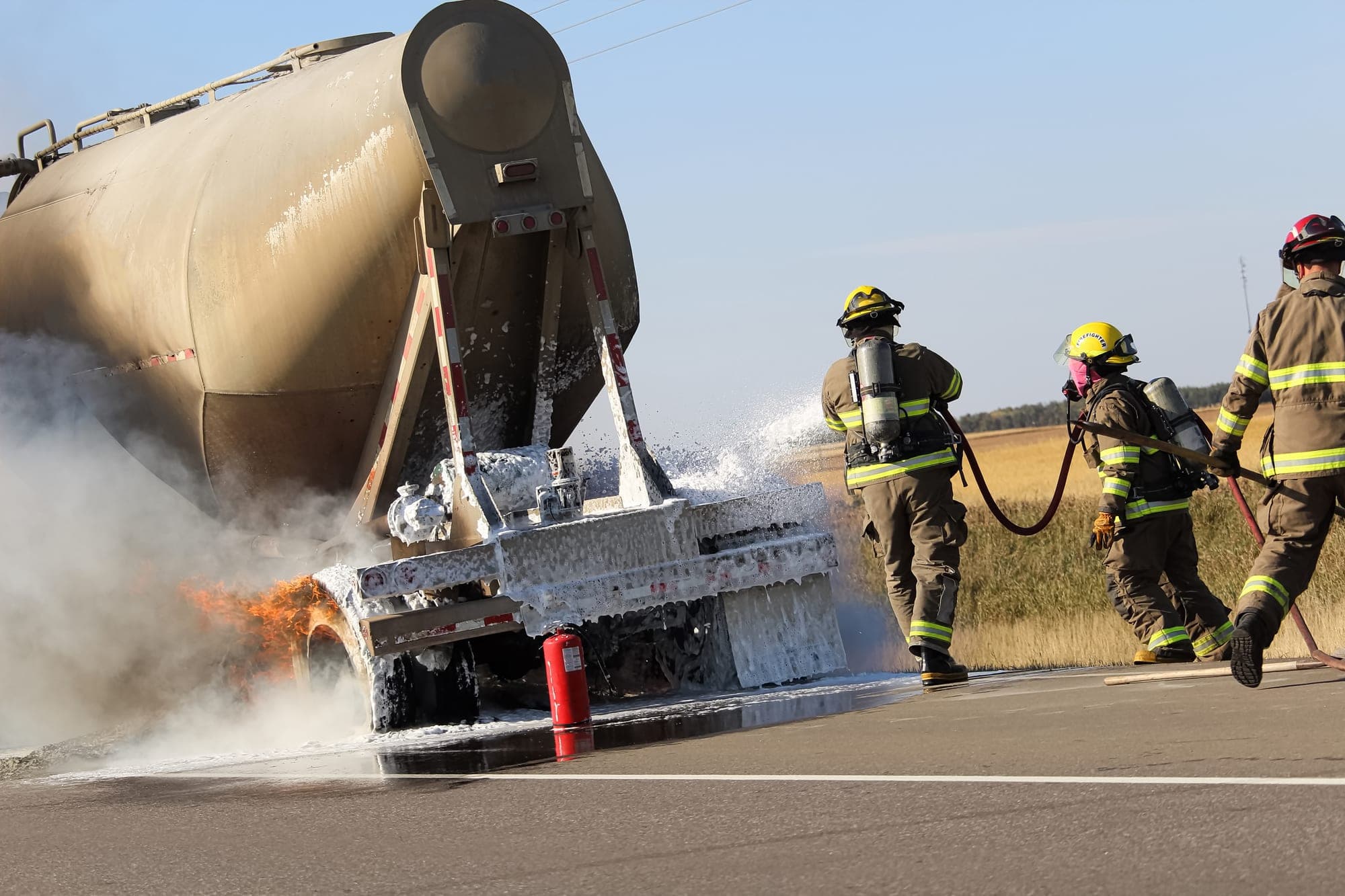 Firefighters spraying foam on a burning tanker trailer