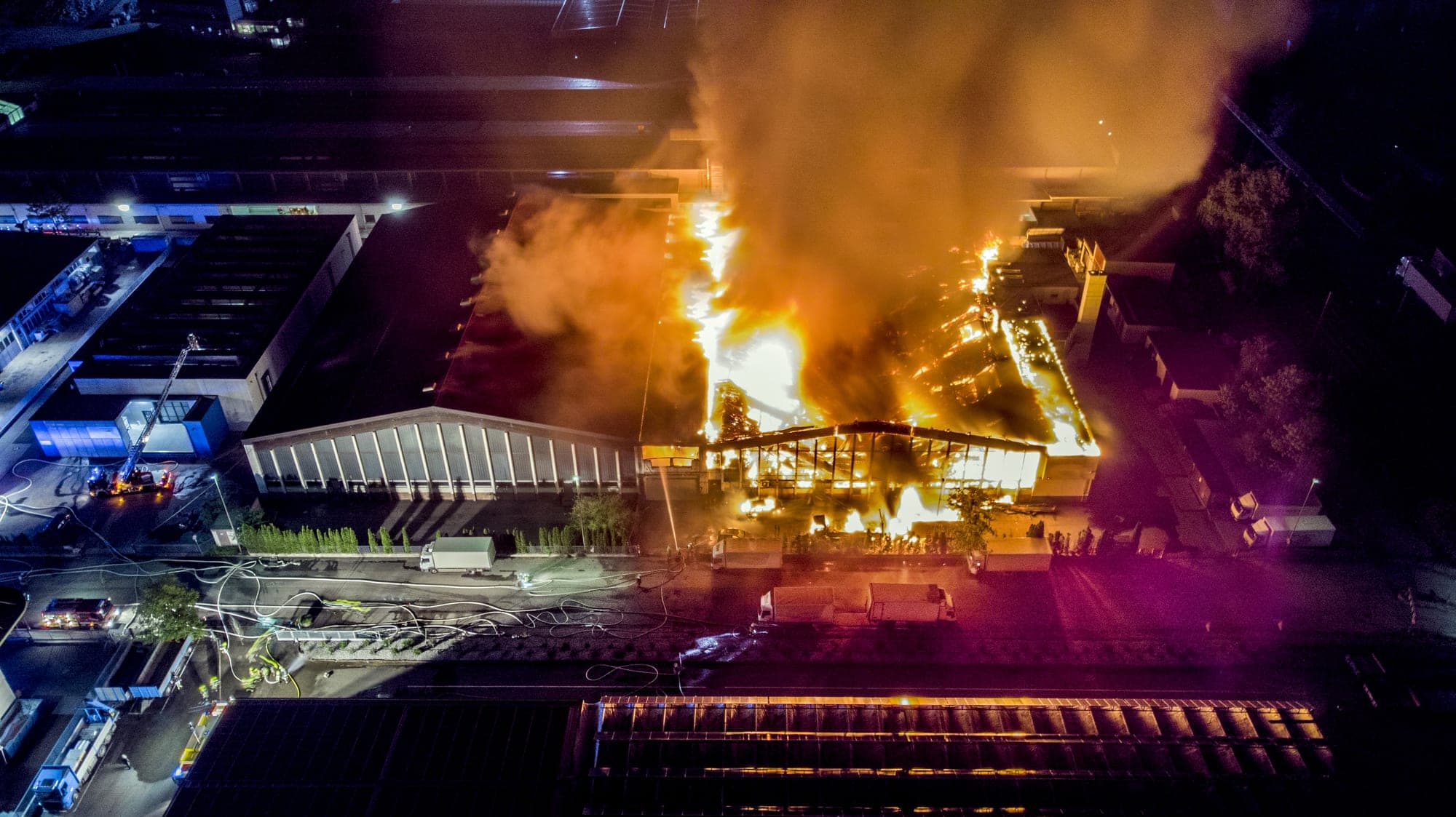 Aerial view of an industrial warehouse burning at night