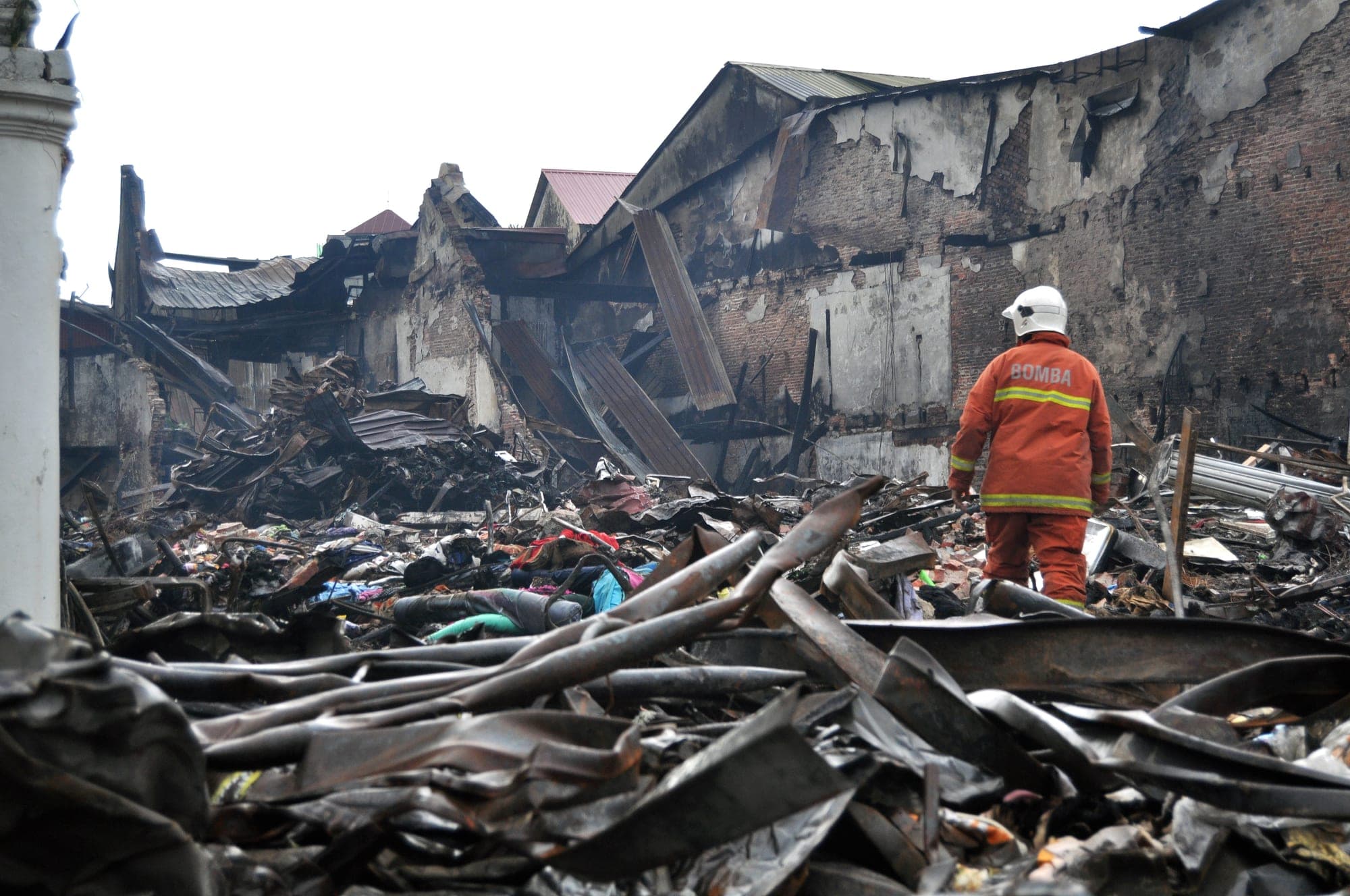 Firefighter walking through fire-gutted industrial ruins