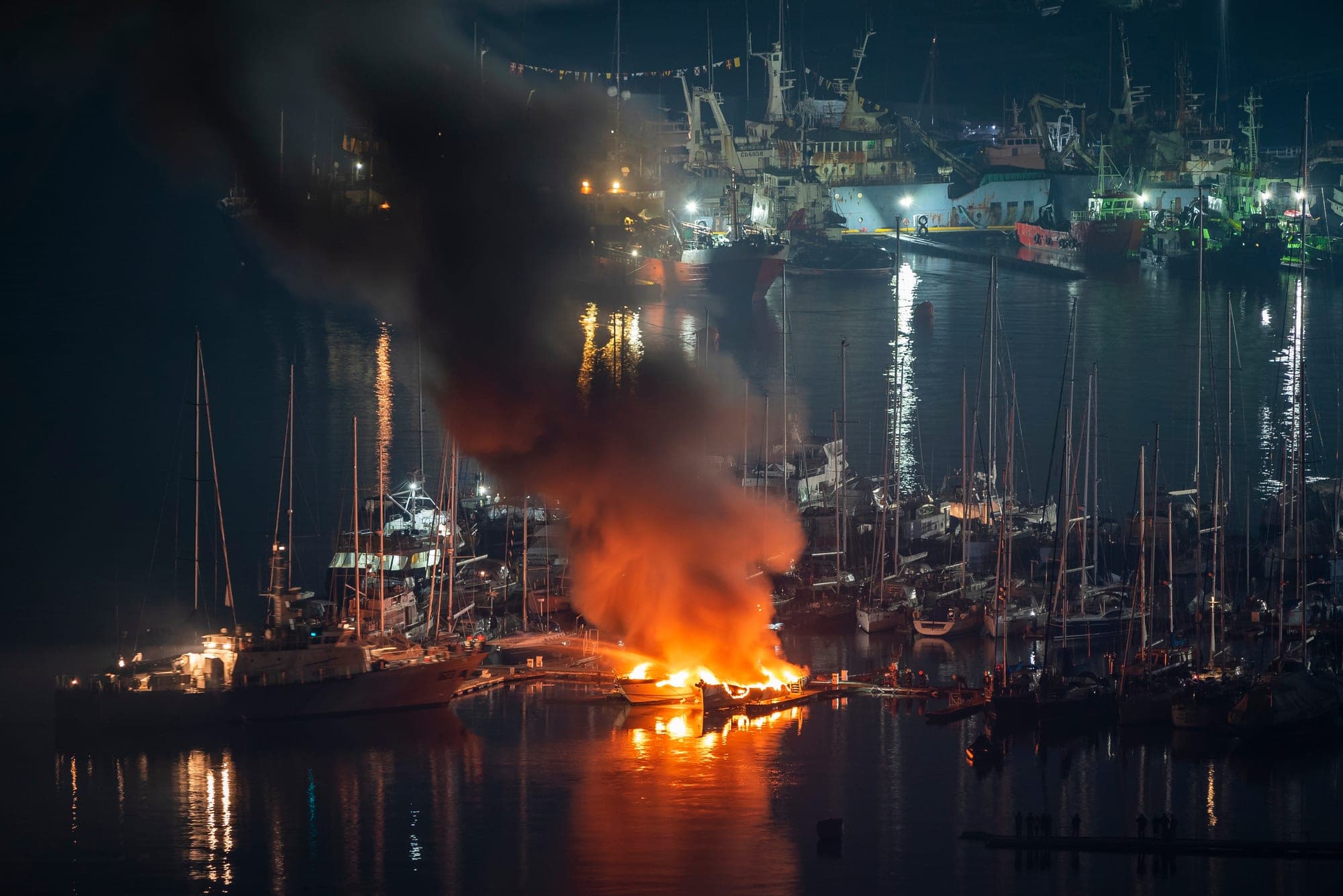 Boat fire lighting up a crowded marina at night