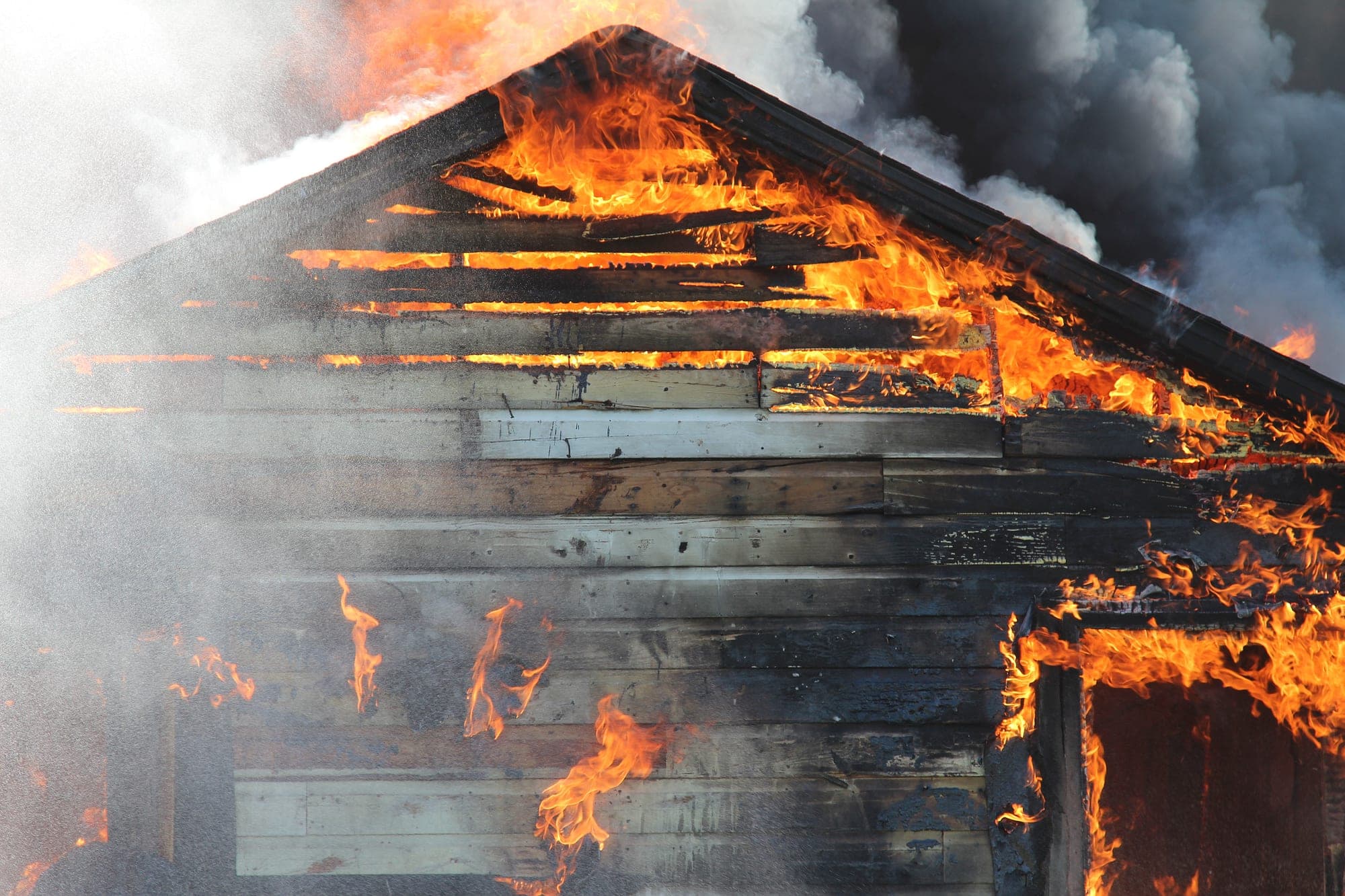 Wood-framed house gable burning with heavy smoke