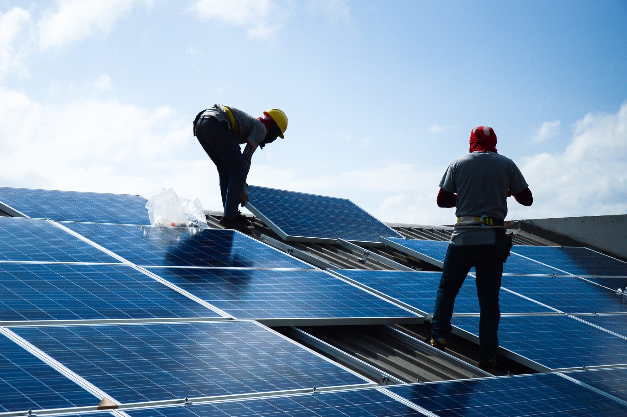Workers installing solar panels on a metal roof