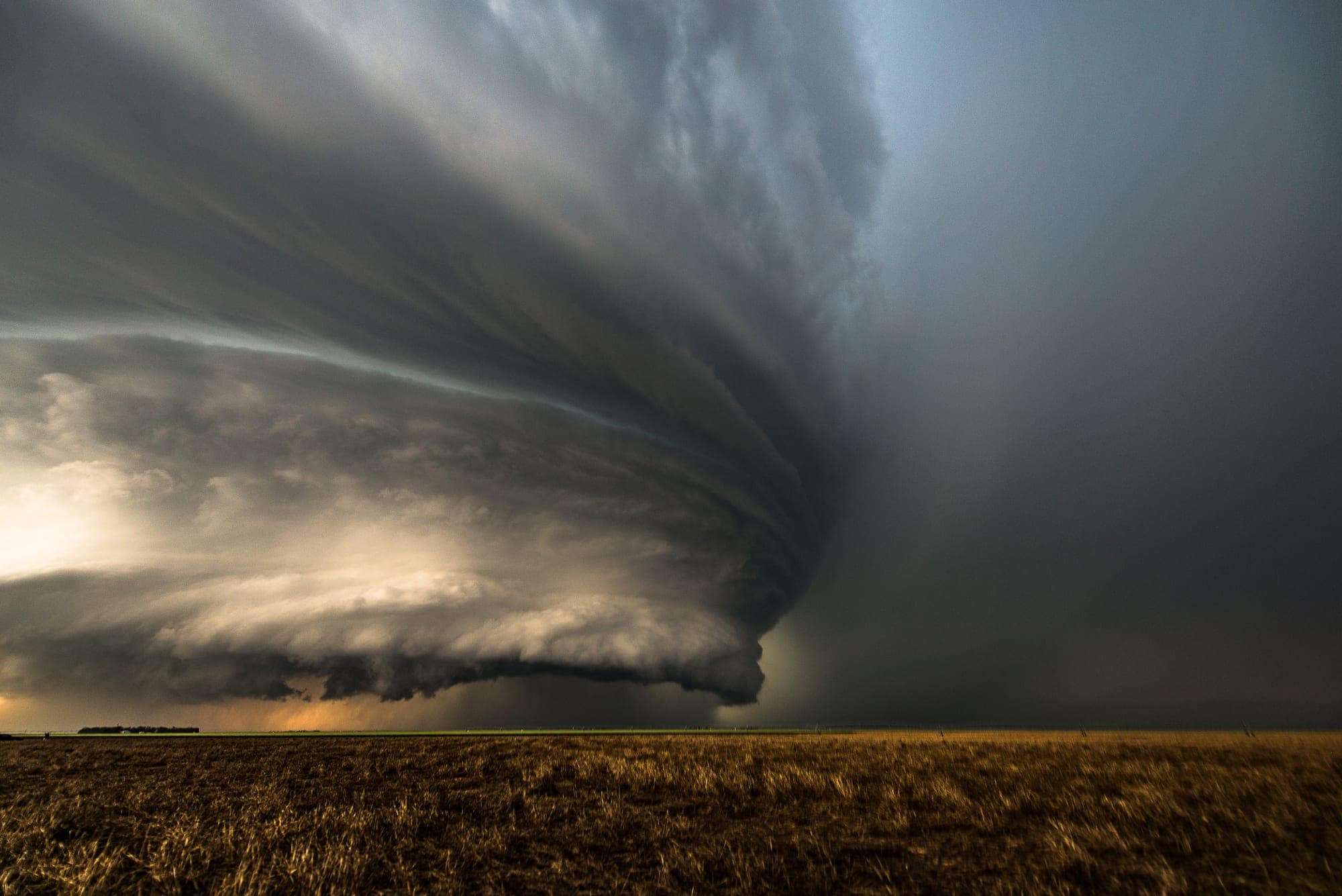 Supercell thunderstorm looming over open prairie fields