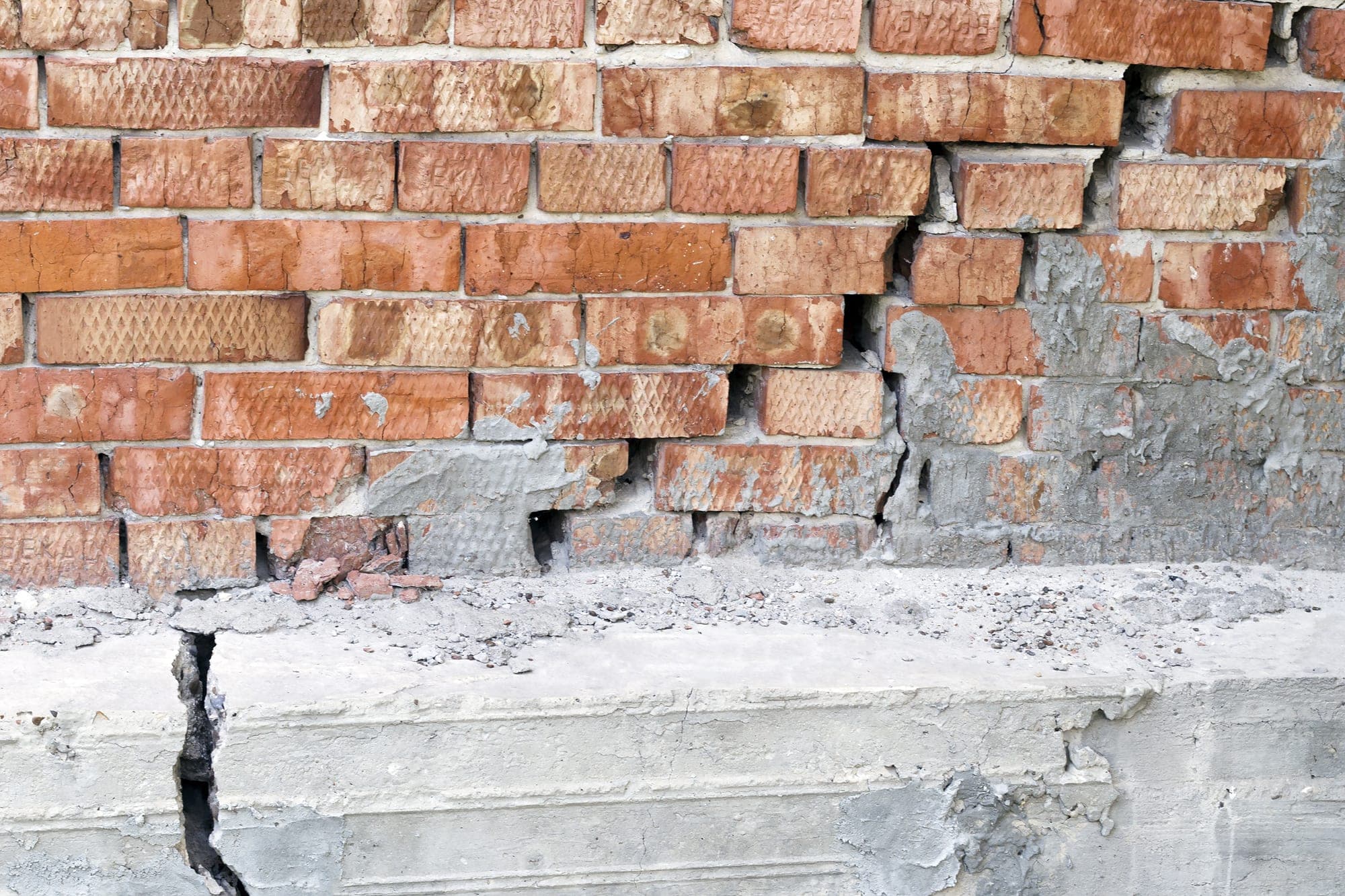 Cracked, shifting brick wall above a concrete foundation