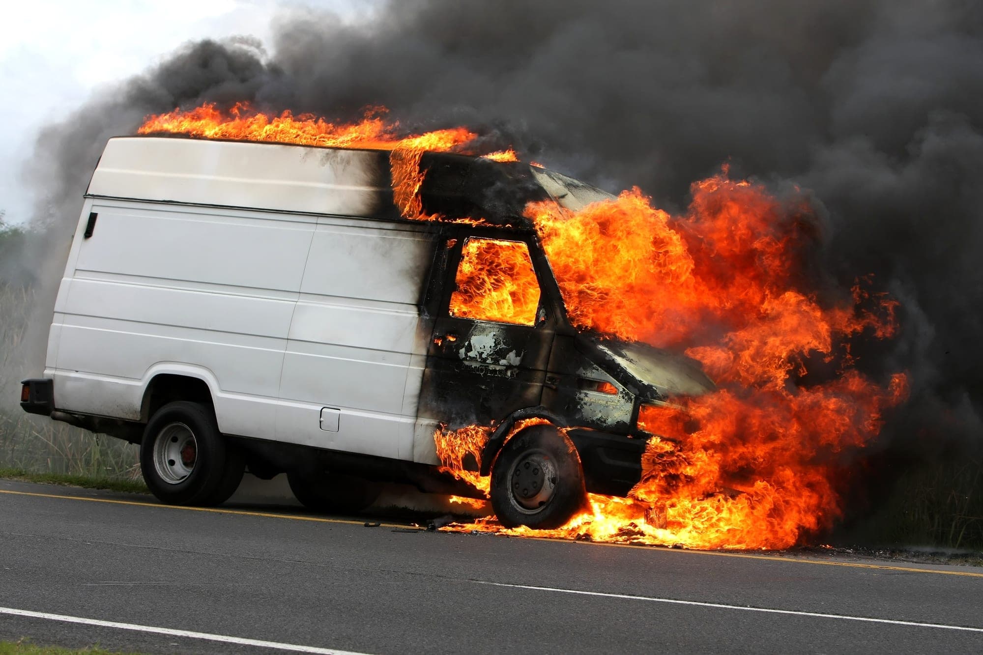 Cargo van engulfed in flames on a roadside