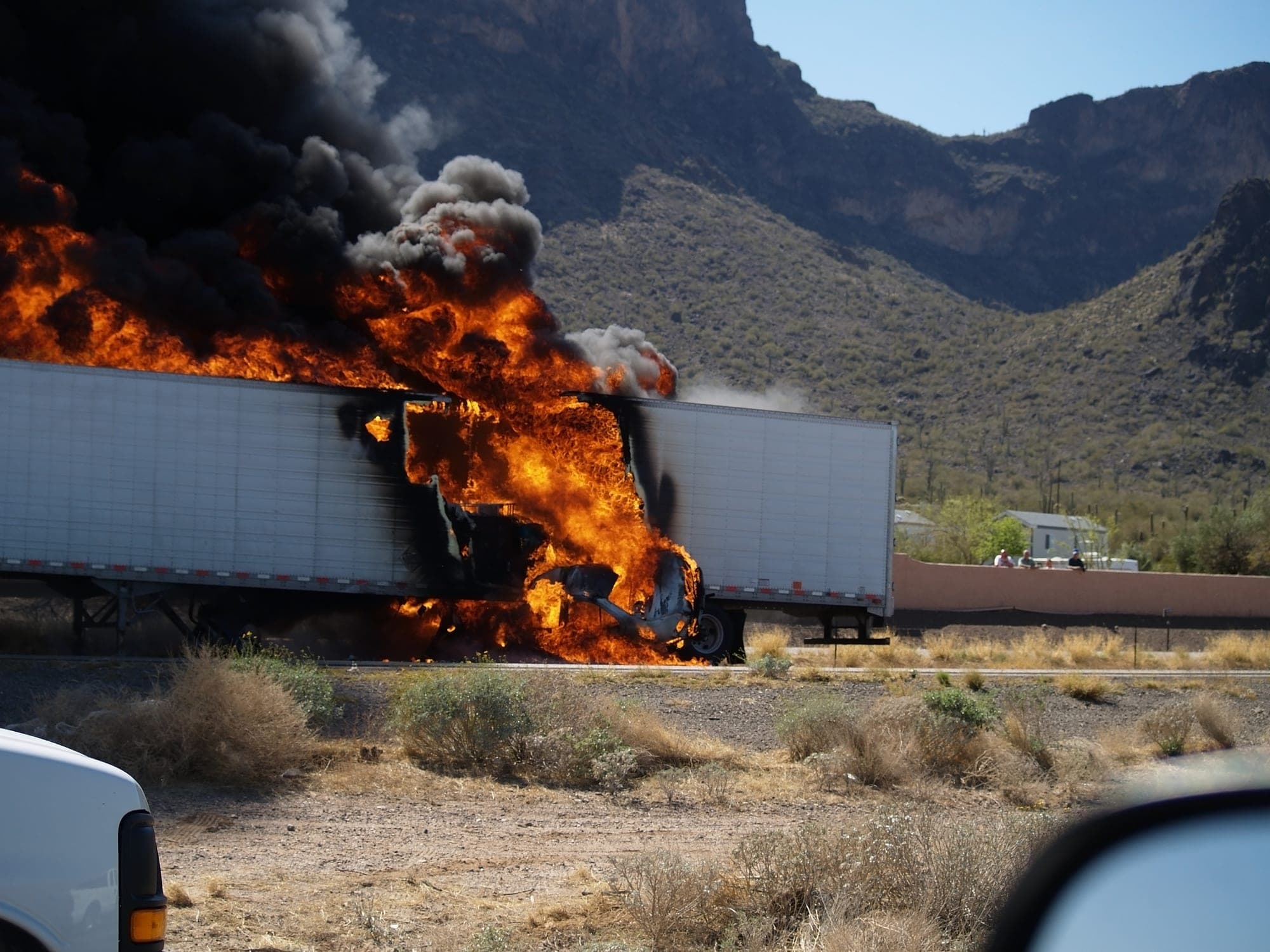 Semi-trailer fire burning beside a desert highway